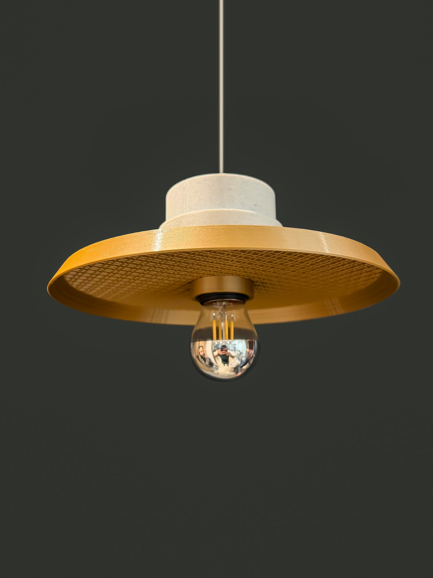Off shot of Ora Drop pendant light in bronze colour with a reflector bulb on a dark background