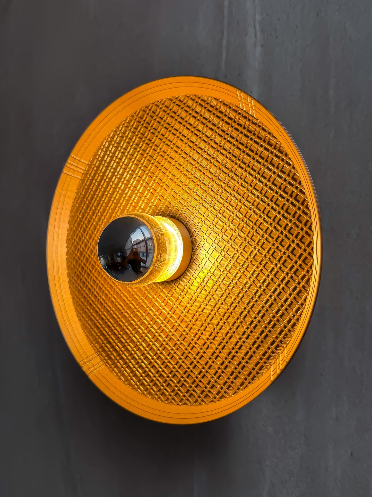Side angled on shot of Ora wall light with textured surface and a reflector bulb on a gray background