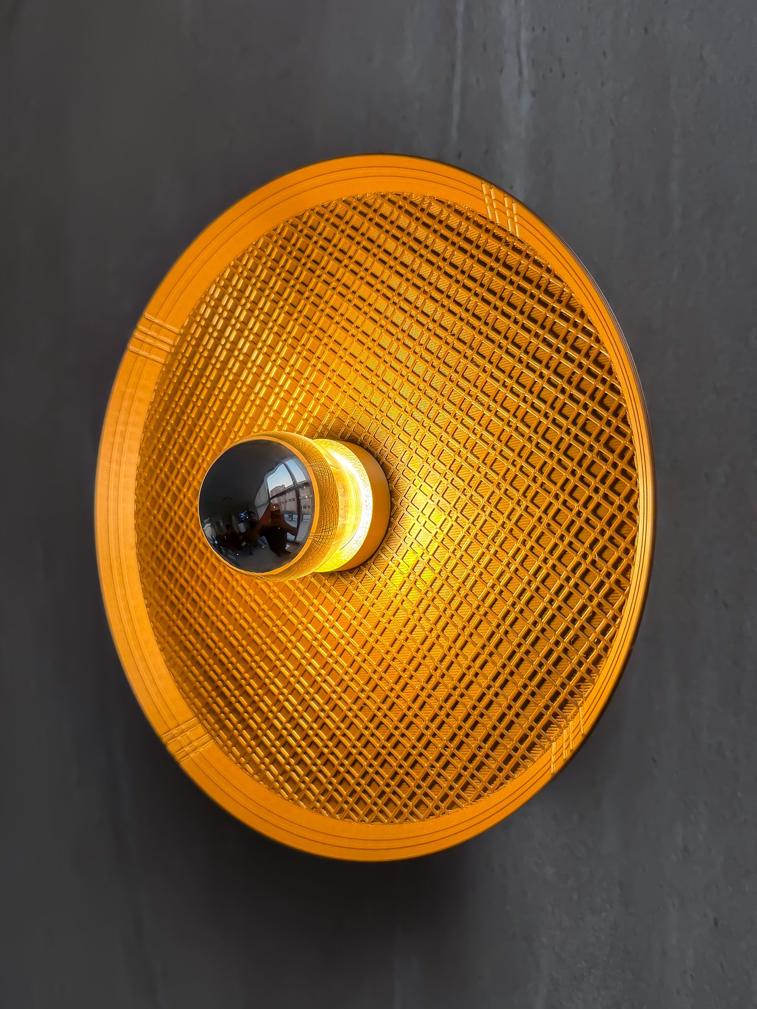 Side angled on shot of Ora wall light with textured surface and a reflector bulb on a gray background