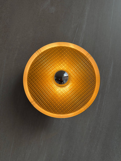 On shot of Ora wall light with textured surface and a reflector bulb on a dark gray background