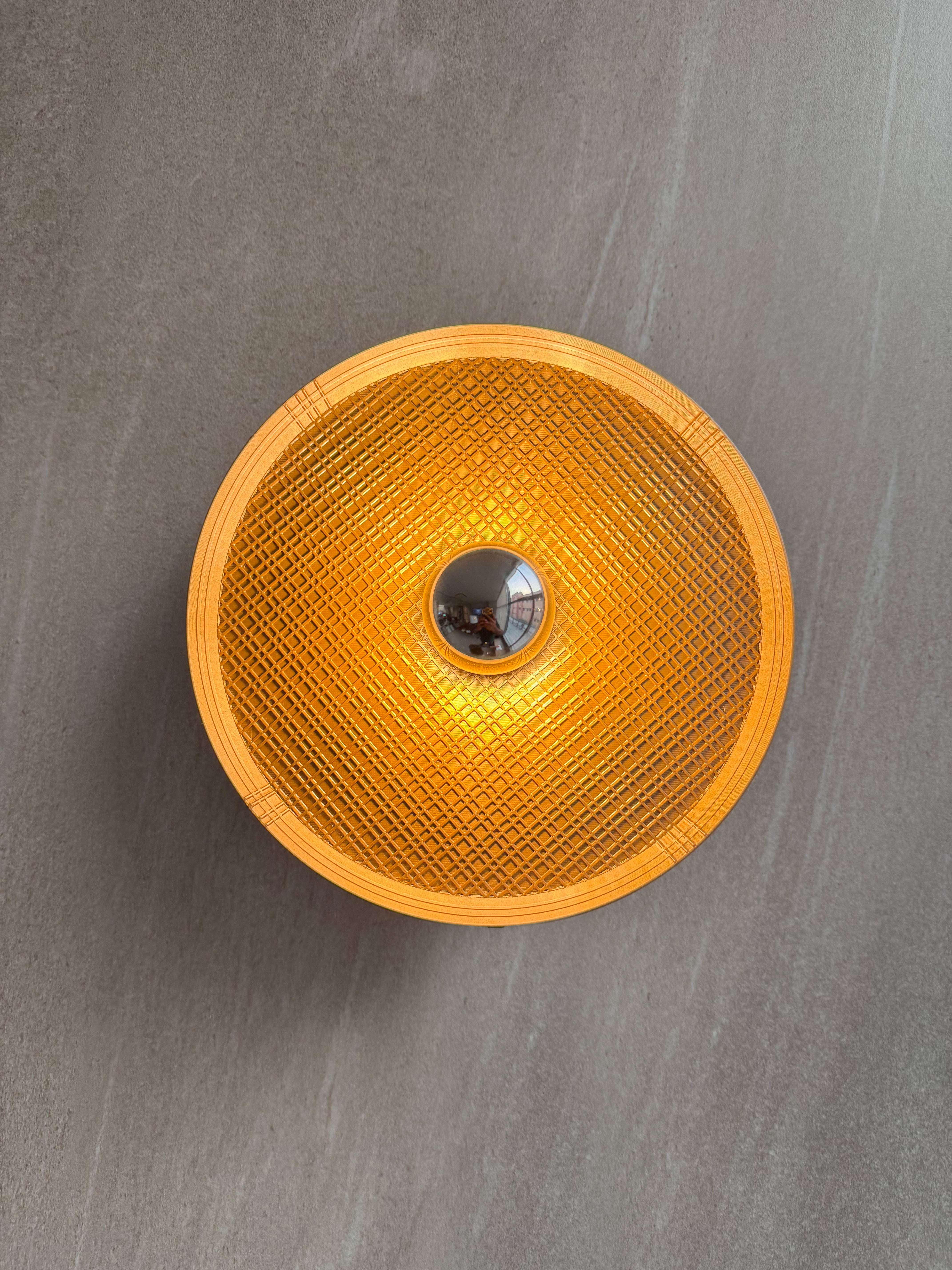 On shot of Ora wall light with textured surface and a reflector bulb on a gray background