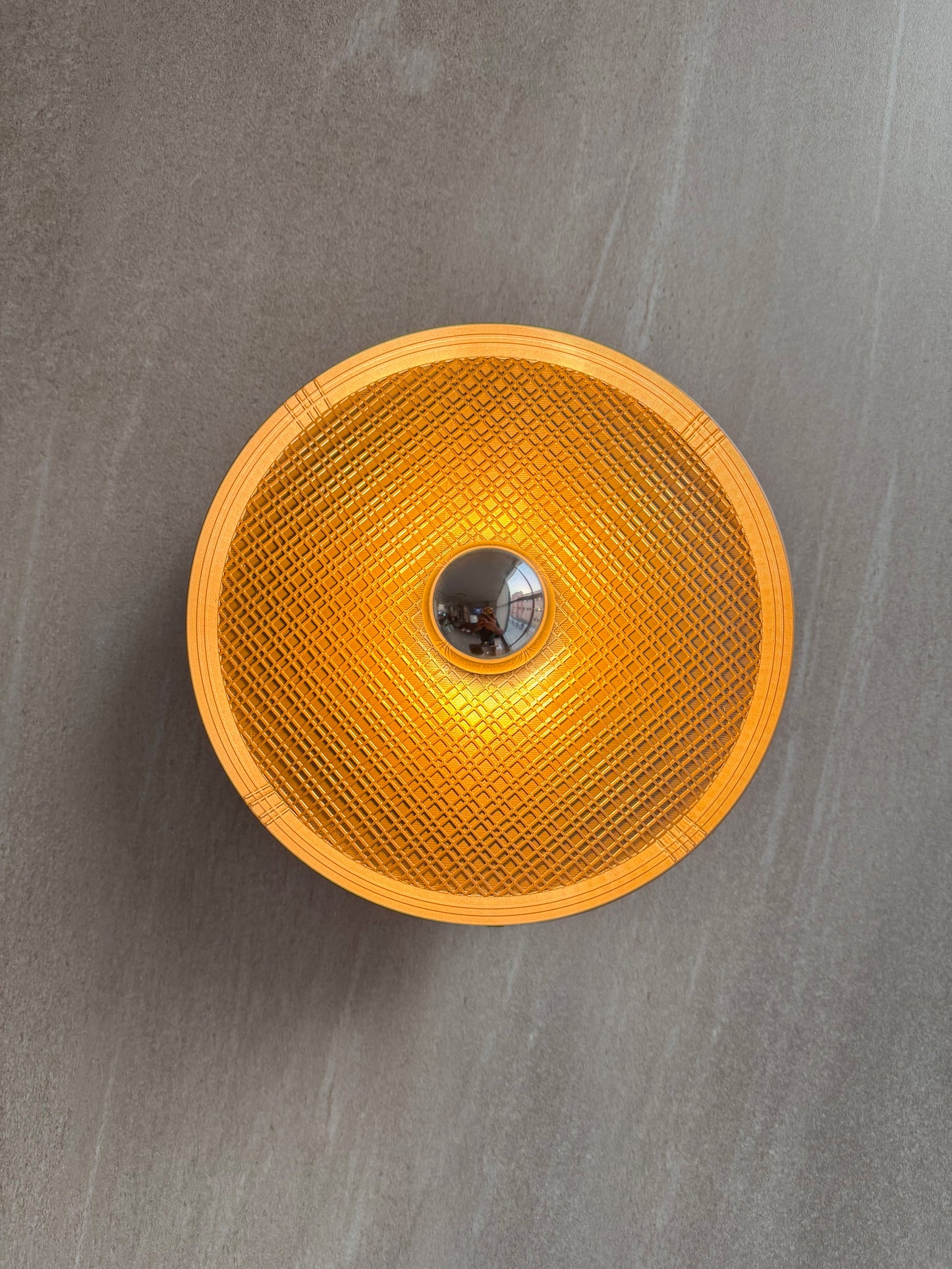 On shot of Ora wall light with textured surface and a reflector bulb on a gray background