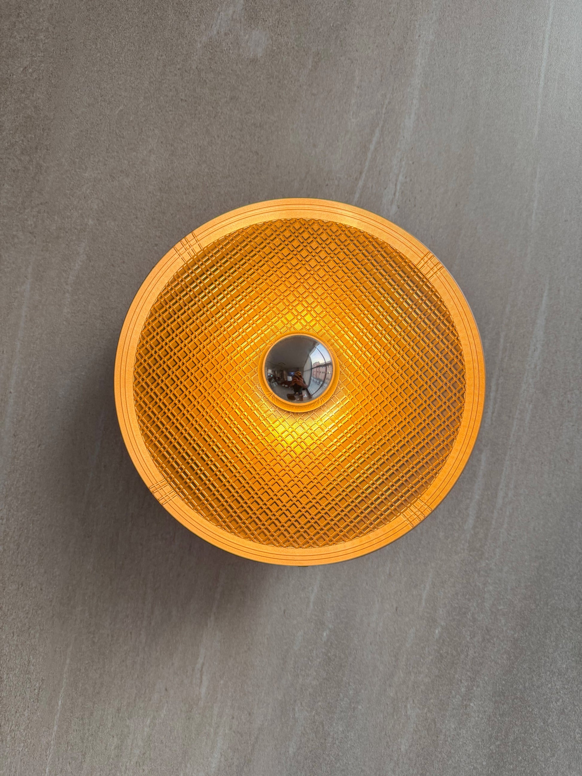 On shot of Ora wall light with textured surface and a reflector bulb on a gray background