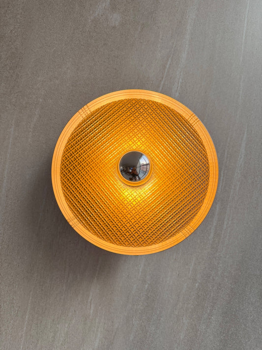 On shot of Ora wall light with textured surface and a reflector bulb on a gray background