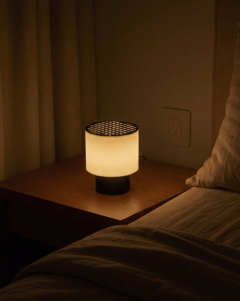 The Poco Circle Lamp featuring a warm, glowing cylindrical shade, a dark circular base, and a striking dark honeycomb-patterned top diffuser.
