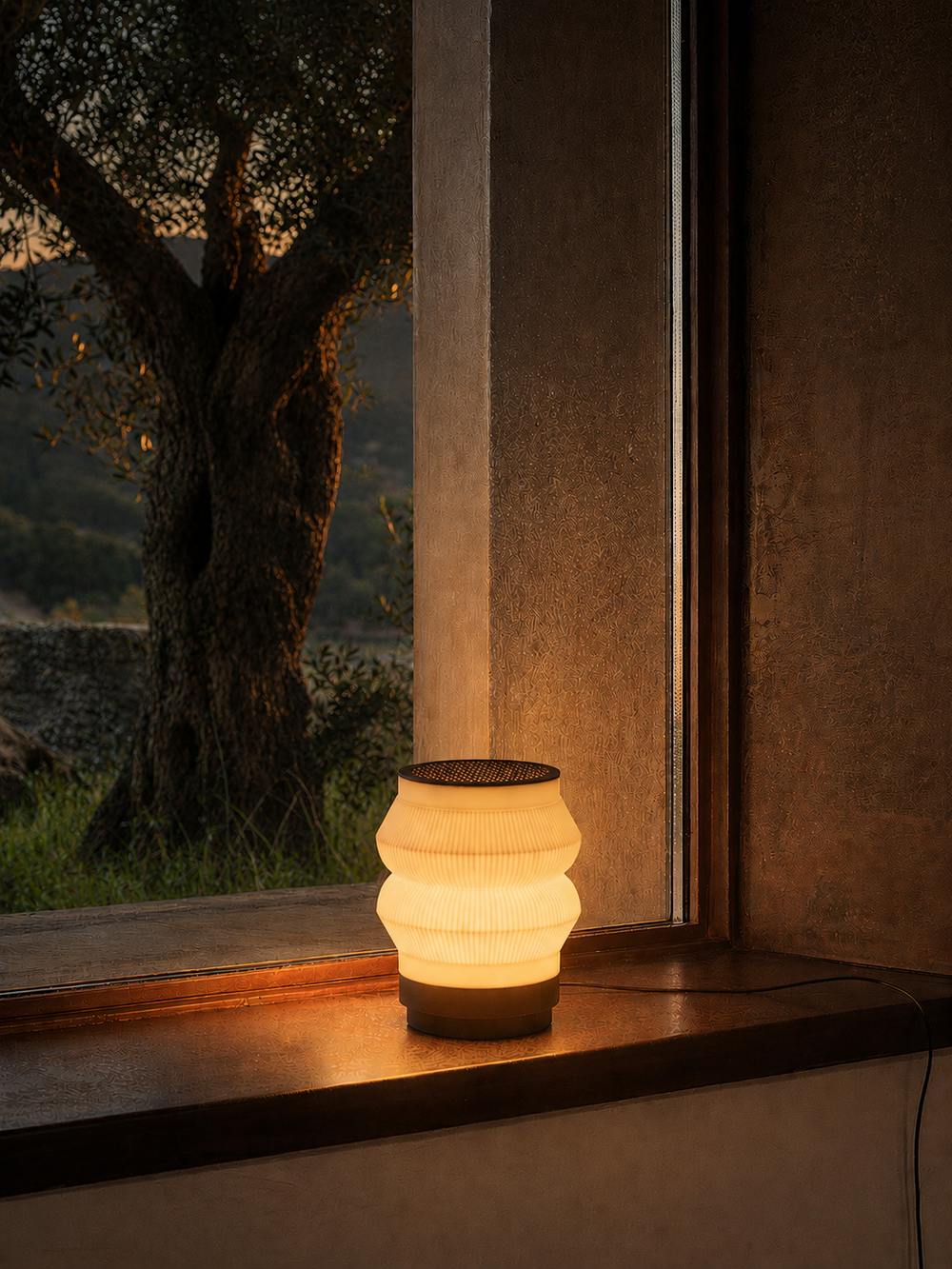 A warmly lit, wireless Stacko Go Lamp radiating a cozy light, highlighting its unique geometric body built from modular, rearrangeable rings resting on a dark base.