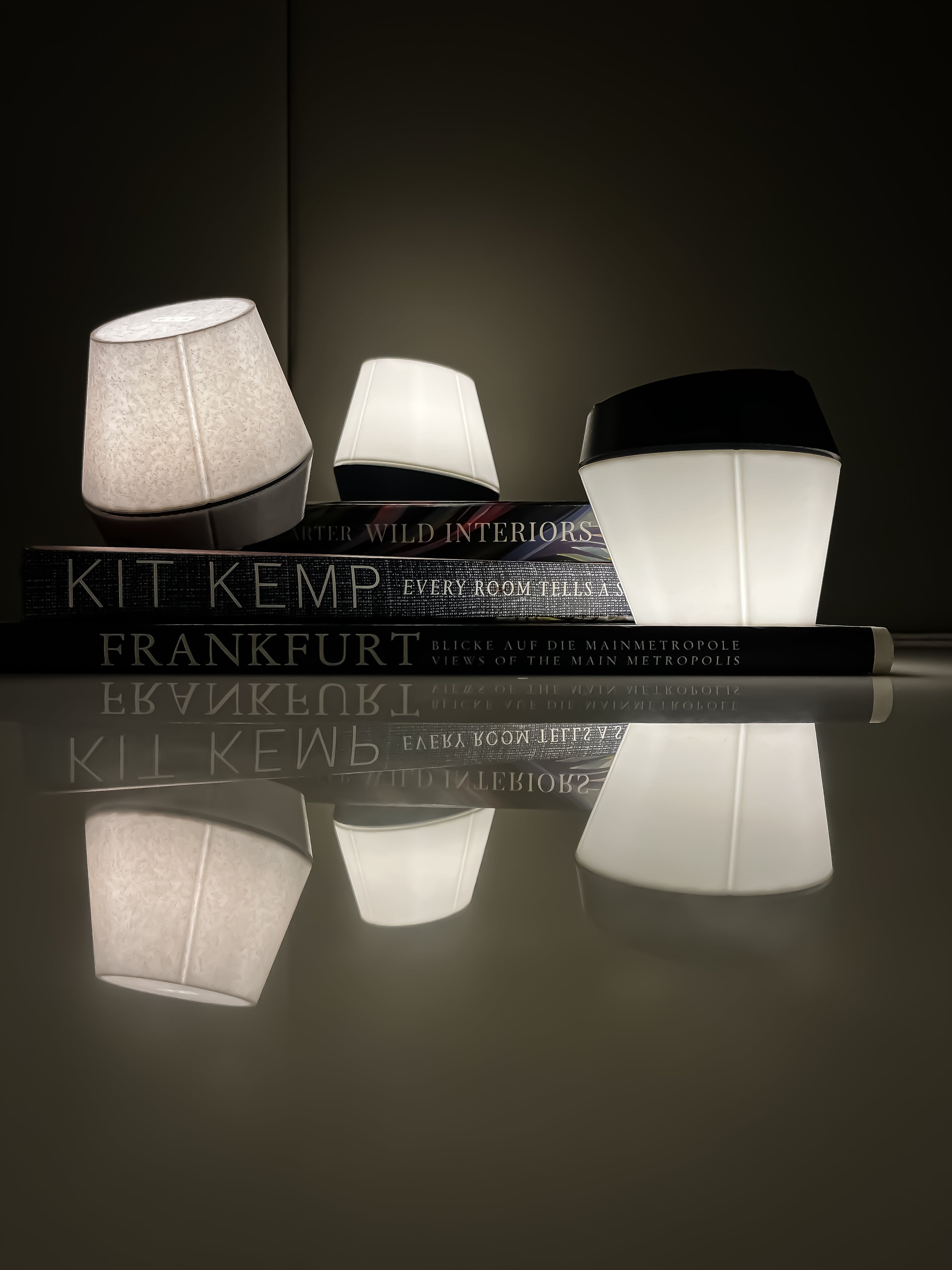 Compact wireless designer lights in an artistic composition, illuminating books with their sophisticated glow.